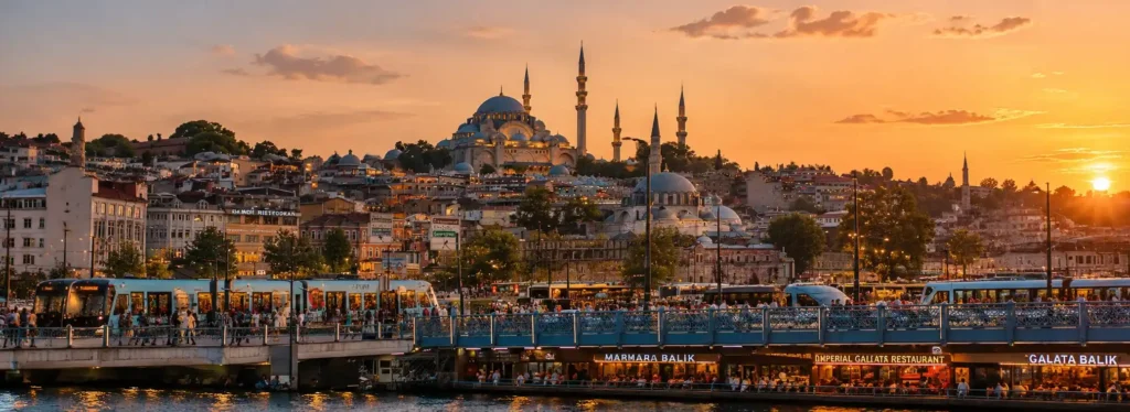 Istanbul trams crossing Galata Bridge with the Süleymaniye Mosque and historic city skyline at sunset